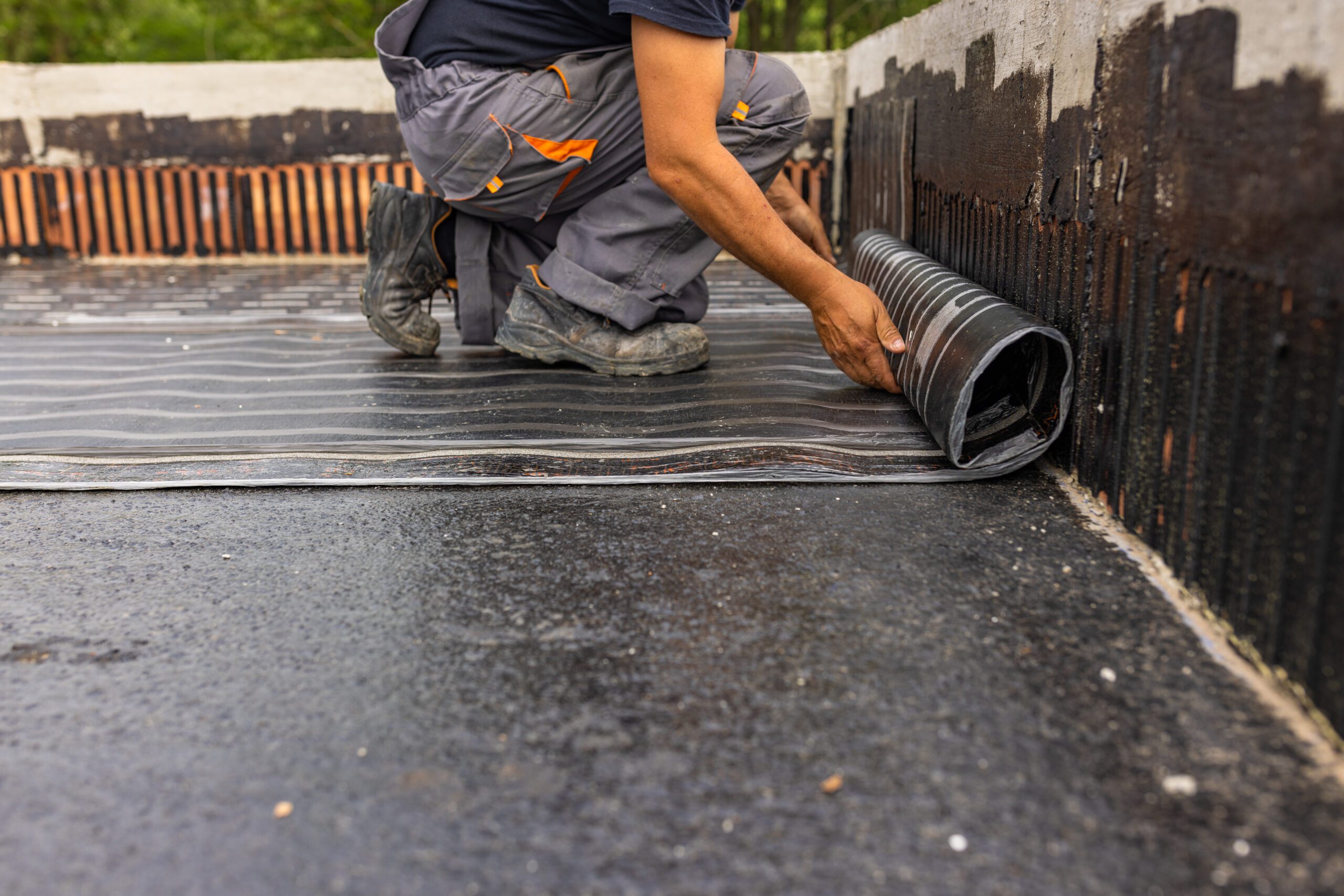 Worker laying the vapor barrier for the roof, bituminous membrane to be welded with flame. Ice and water shield vs. traditional underlayment.