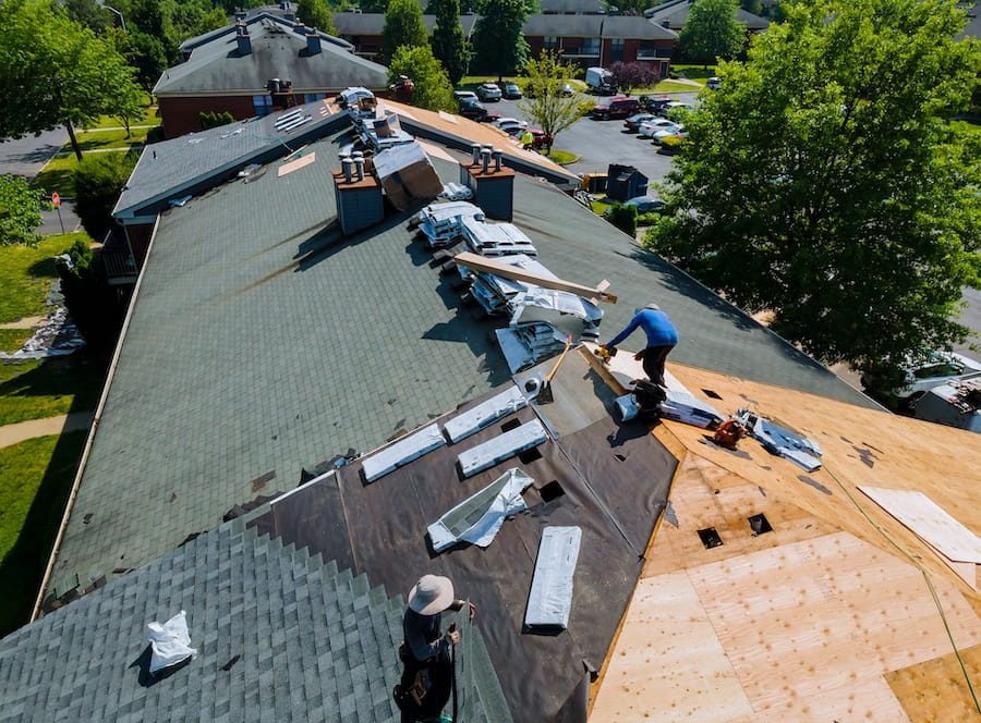 Workers Replacing Asphalt Shingles on an Apartment Roof