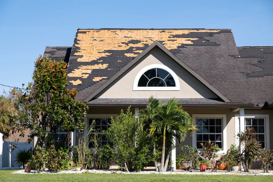 Storm-damaged roof with missing shingles and visible wind damage