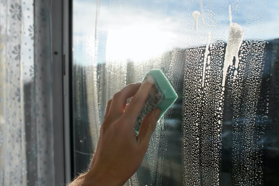 Sponge Cleaning a Window on a Bright Day