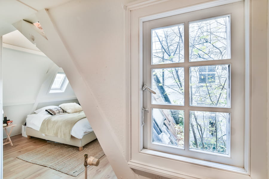 Bedroom with Bedding and Window View of Trees